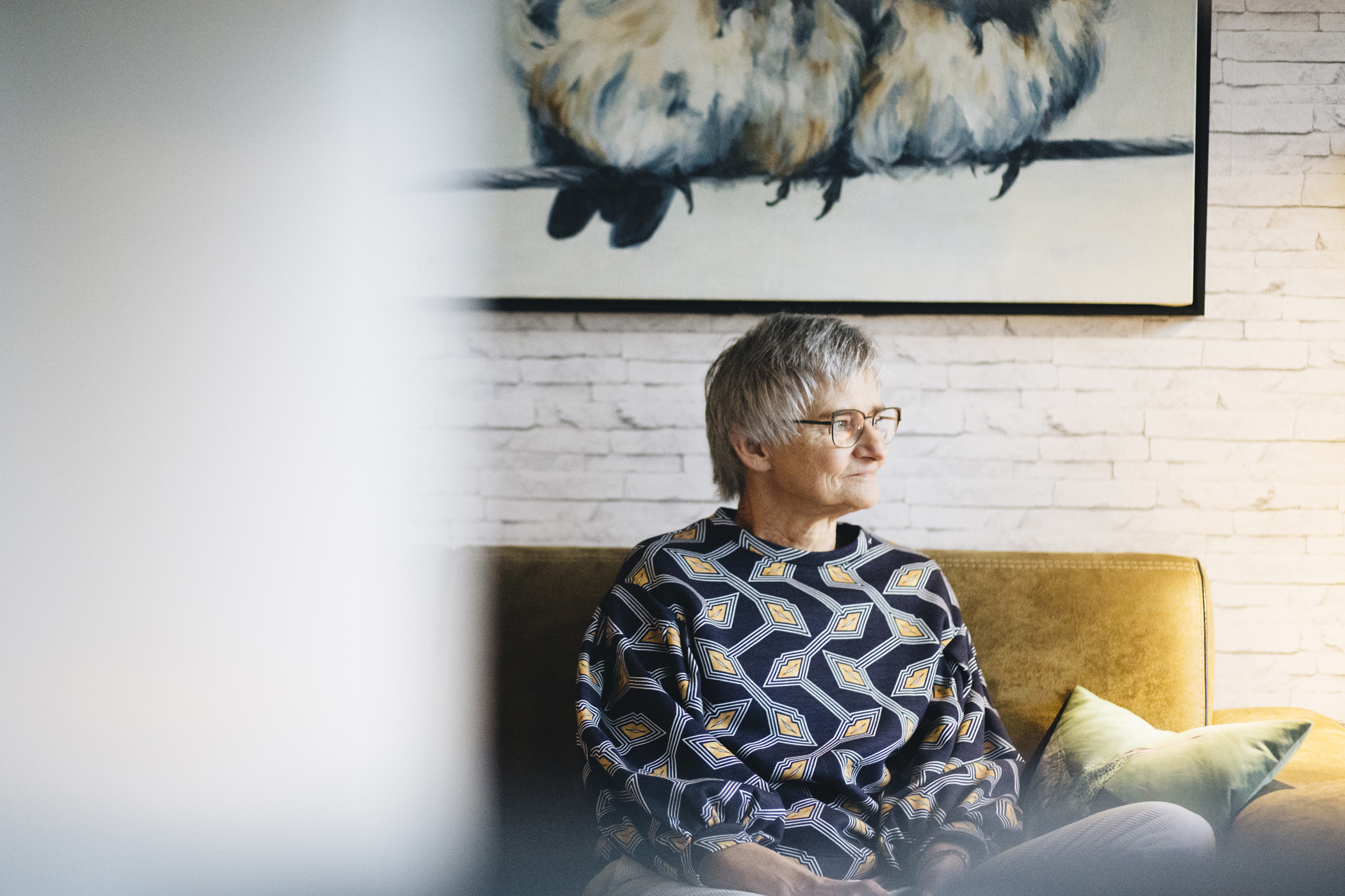 Foto van Almut zittend op de bank in haar woonkamer.