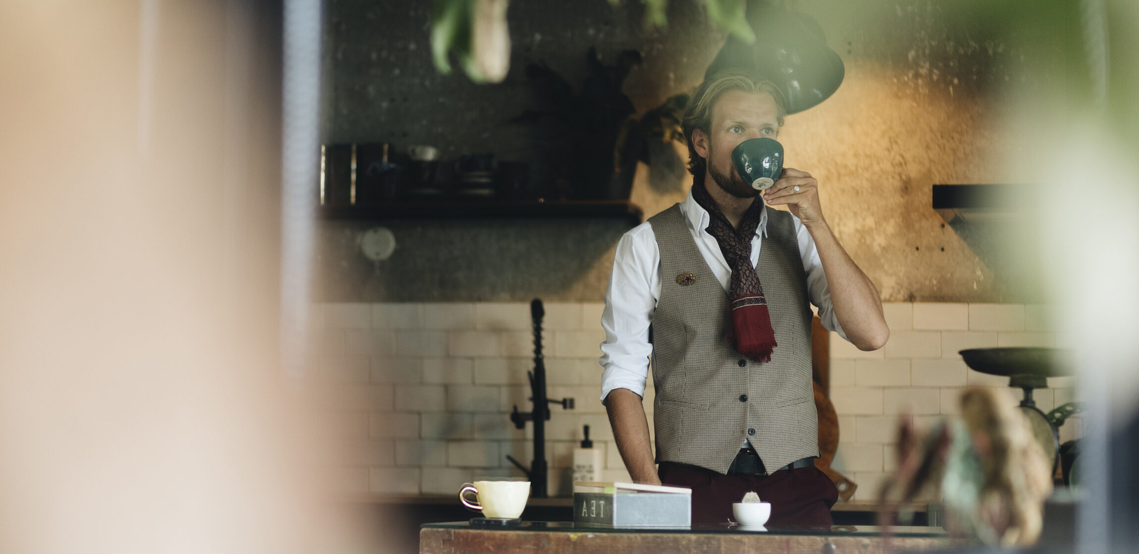 Foto van Bernard in zijn keuken, terwijl hij een kopje koffie drinkt.